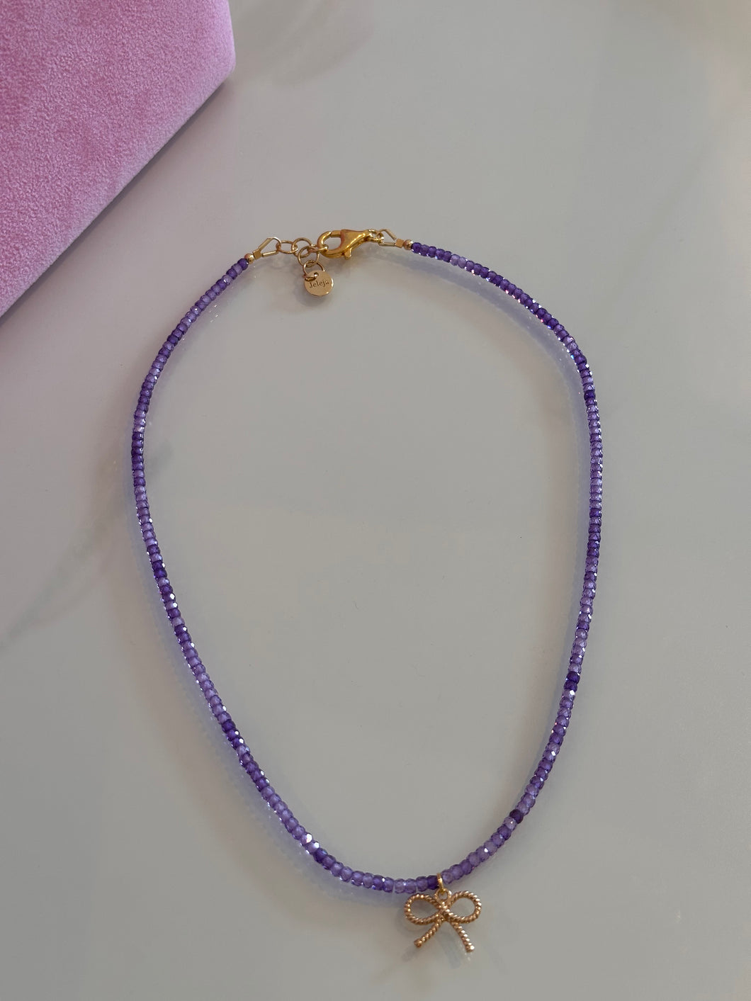 Beaded necklace with amethyst and gold plated silver bow pendant